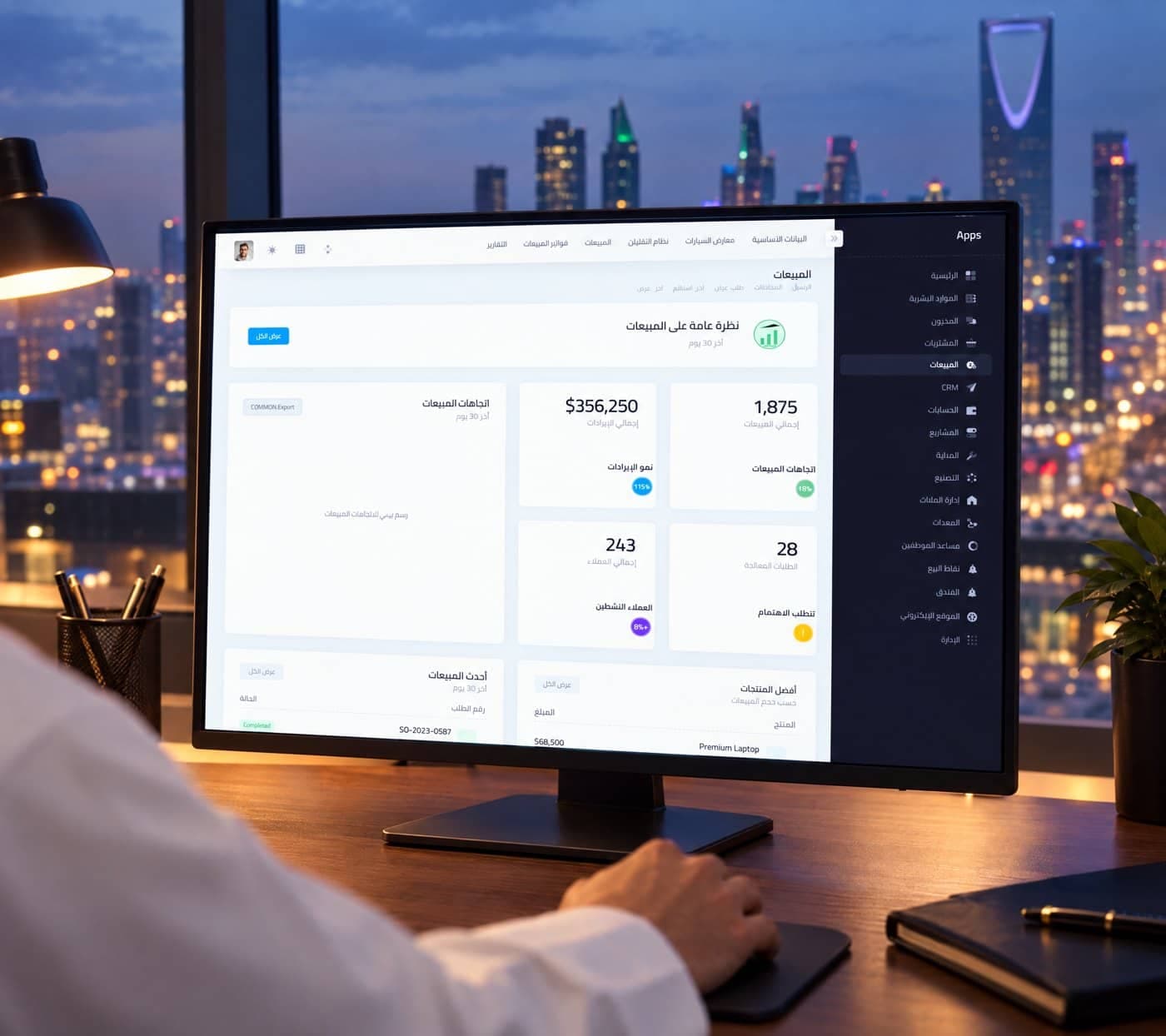 لوحة مبيعات فالكون ERP على شاشة مكتب، وخلفها أفق الرياض